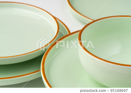 A set of pastel green ceramic tableware with orange outlines 95188697