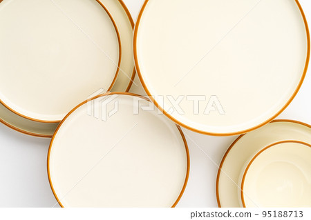 A set of white and brown ceramic plates on a white background. Top view A set of white and brown ceramic plates on a white background. Top view 95188713