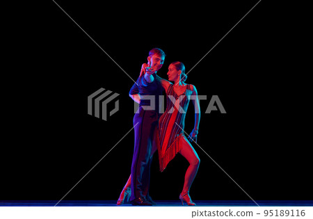 Two dancing people, ballroom dancers in elegance outfits in motion, action over dark background in neon light. Concept of art, music, dance, emotions. Two dancing people, ballroom dancers in elegance outfits in motion, action over dark background in neon light. Concept of art, music, dance, emotions. 95189116