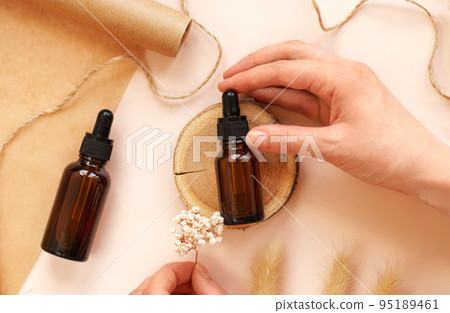 Two glass amber bottles with black cap flat lay. DIY scene. POV. Beauty products packaging scene. Dropper bottle with pipette on wooden podium. Natural eco-friendly cosmetics presentation Two glass amber bottles with black cap flat lay. DIY scene. POV. Beauty products packaging scene. Dropper bottle with pipette on wooden podium. Natural eco-friendly cosmetics presentation 95189461