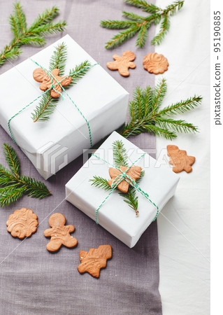 Christmas gifts wrapped in white paper and decorated with spruce sprigs and gingerbread cookies Christmas gifts wrapped in white paper and decorated with spruce sprigs and gingerbread cookies 95190885