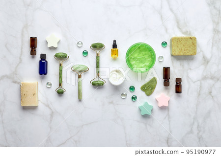 Cosmetic skin care products, jade stone face massager, creams, gel and oil. Roller massage of the face. Flat lay, top view Cosmetic skin care products, jade stone face massager, creams, gel and oil. Roller massage of the face. Flat lay, top view 95190977