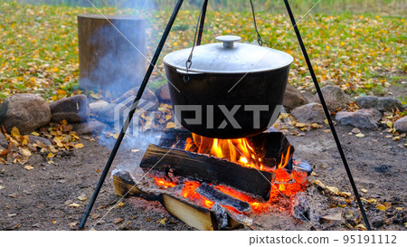 Cooking in a pot on an open fire in nature. Bowler on a bonfire in the forest. 95191112