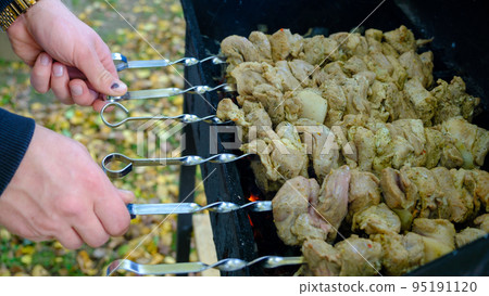 pork shashlik kebab, roasted on skewers, roasted on the grill, on coals. party and juicy meat. Concept of lunch, dinner, restaurant, guests, celebration. the cook is working on the grill 95191120