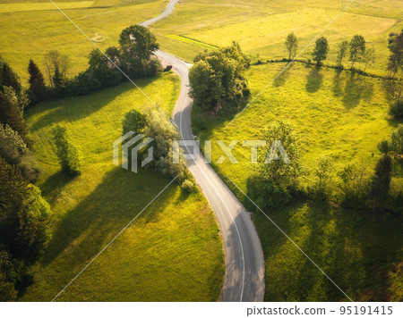 Aerial view of road in green meadows and hills at sunset in summer Aerial view of road in green meadows and hills at sunset in summer 95191415