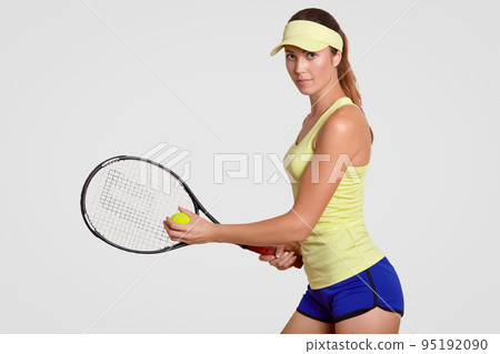 People, sport and rest concept. Sideways shot of fitness active female tennis player holds racket and ball, ready to play and hit, isolated over white background. Healthy lifestyle and hobby. 95192090