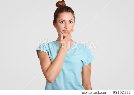 Thoughtful puzzled woman with hesitant expression, holds chin, dressed in casual clothes, ponders on something, isolated over white background. Student being deep in thoughts. Hesitation concept Thoughtful puzzled woman with hesitant expression, holds chin, dressed in casual clothes, ponders on something, isolated over white background. Student being deep in thoughts. Hesitation concept 95192152