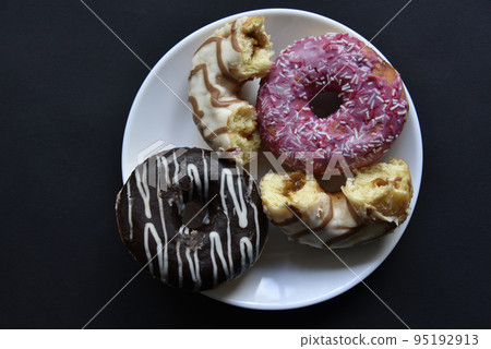 Delicious sweet donuts on a white plate. Donuts in glaze with filling close-up. 95192913