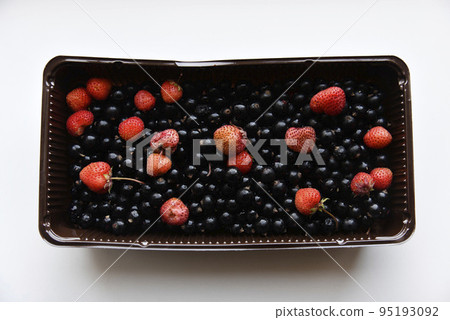 Strawberries and black currants in plastic containers. Delicious fresh berries in a box on a white background. Strawberries and black currants in plastic containers. Delicious fresh berries in a box on a white background. 95193092