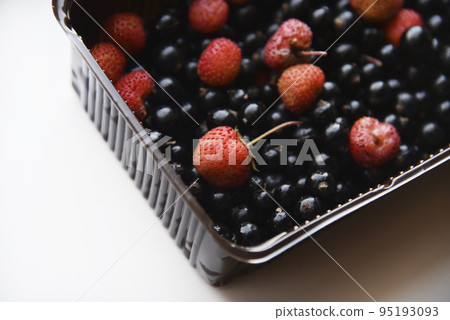 Strawberries and black currants in plastic containers. Delicious fresh berries in a box on a white background. Strawberries and black currants in plastic containers. Delicious fresh berries in a box on a white background. 95193093