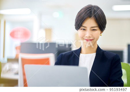 A businesswoman in a suit looking at her computer in the office 95193497