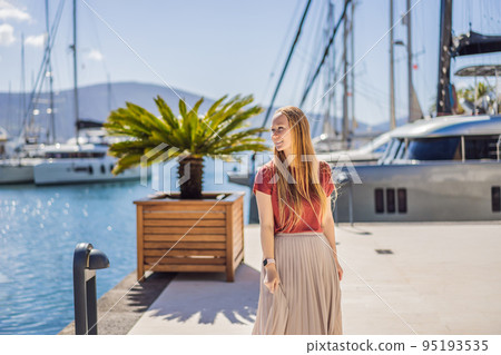 Woman tourist on background of Yacht marina, beautiful Mediterranean landscape in warm colors. Montenegro, Kotor Bay, Tivat city. Porto Montenegro marina view. Go Everywhere. Travel around Montenegro Woman tourist on background of Yacht marina, beautiful Mediterranean landscape in warm colors. Montenegro, Kotor Bay, Tivat city. Porto Montenegro marina view. Go Everywhere. Travel around Montenegro 95193535