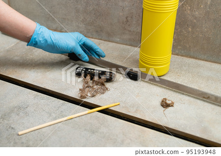Woman removing hair clump from the shower drain. Woman removing hair clump from the shower drain. 95193948