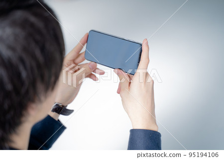 20 多歲的男人在客廳的沙發上用智能手機觀看視頻 20 多歲的男人在客廳的沙發上用智能手機觀看視頻 95194106