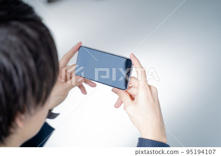 Men in their 20s playing social games on their smartphones-relaxing on the sofa in the living room Men in their 20s playing social games on their smartphones-relaxing on the sofa in the living room 95194107