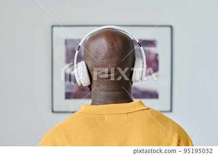 Rear view of African young listening to guide in wireless headphones at art gallery 95195032