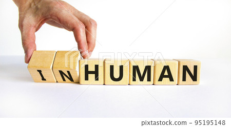 Human or inhuman symbol. Businessman turns wooden cubes and changes the word inhuman to human. Beautiful white table white background, copy space. Business, human or inhuman concept. Human or inhuman symbol. Businessman turns wooden cubes and changes the word inhuman to human. Beautiful white table white background, copy space. Business, human or inhuman concept. 95195148