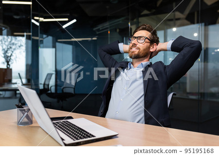 Completion work important project, mature man working inside modern office building using laptop, senior boss with beard and glasses putting hands behind head dreaming and visualizing future plans. 95195168