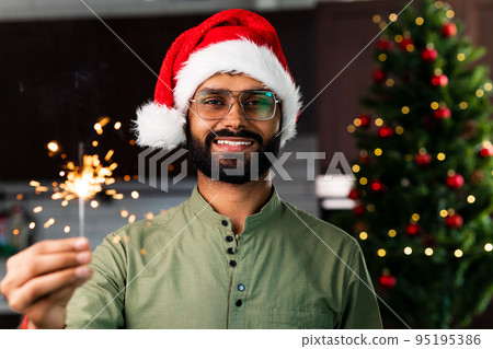 Smiling young latin hispanic man holding a sparkler at home 95195386