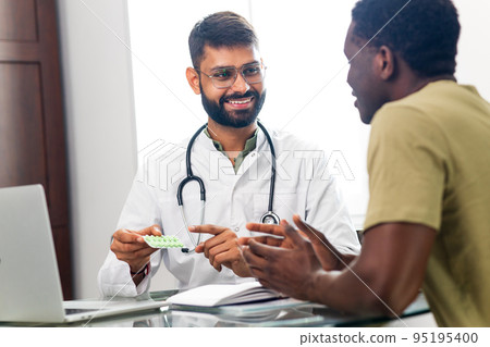 Indian doctor therapist in white coat consulting supporting patient in modern clinic hospital Indian doctor therapist in white coat consulting supporting patient in modern clinic hospital 95195400