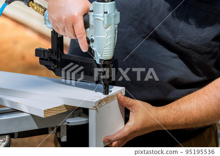 Carpenter connects assembly for wood boards with nails with pneumatic air gun Carpenter connects assembly for wood boards with nails with pneumatic air gun 95195536