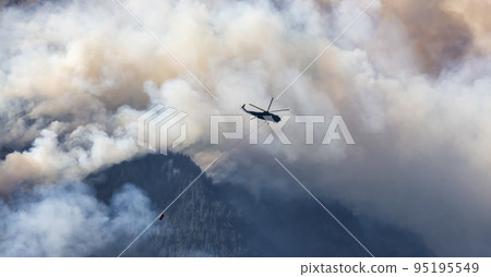 Wildfire Service Helicopter flying over BC Forest Fire and Smoke on the mountain near Hope 95195549