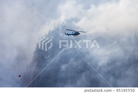 Wildfire Service Helicopter flying over BC Forest Fire and Smoke on the mountain near Hope 95195550