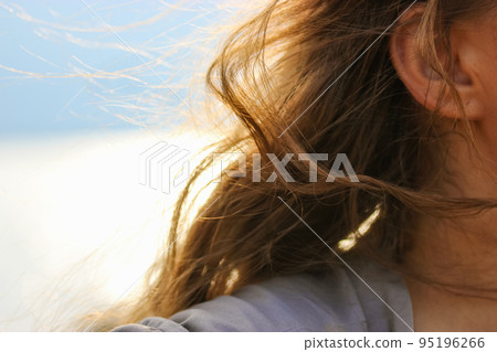 A breeze in her brown wavy curly hair selective focus. Portrait of a young woman, a girl with hair fluttering in the wind. A breezy windy day by the sea. Solo traveling, dreaming concept. Female mood. A breeze in her brown wavy curly hair selective focus. Portrait of a young woman, a girl with hair fluttering in the wind. A breezy windy day by the sea. Solo traveling, dreaming concept. Female mood. 95196266