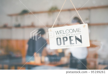 wooden "Open" sign hangs at the cafe's or restaurant's entrance. 95199261