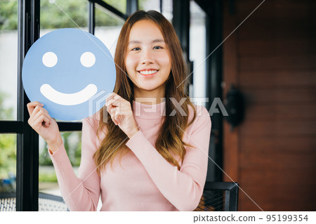 woman smiling showing excellent rating with smiley face icon on blue circle paper woman smiling showing excellent rating with smiley face icon on blue circle paper 95199354