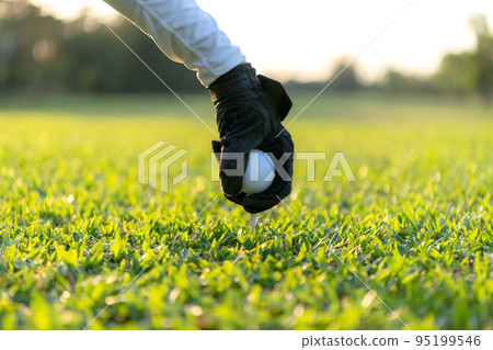 Close up hand asian sporty woman putting golf ball on tee with club in golf course on evening on time Close up hand asian sporty woman putting golf ball on tee with club in golf course on evening on time 95199546