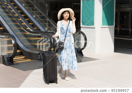 A woman walking with a suitcase in front of an escalator Travel image 95199957