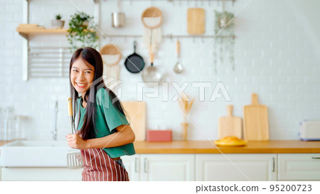 Asian young woman dancing in kitchen room. Female happy and relaxing at free time on weekend 95200723