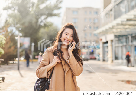 Lifestyle portrait happy Asian kazakh woman talking on mobile phone and laughing Lifestyle portrait happy Asian kazakh woman talking on mobile phone and laughing 95201304