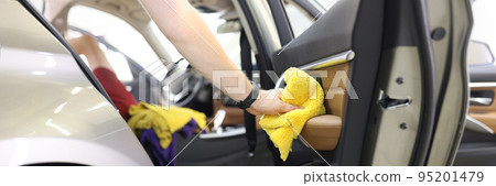 Car wash service worker wipes car door with rag wipes 95201479