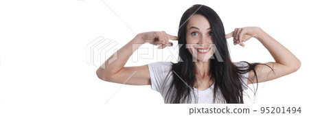 Portrait of smiling woman puts fingers in ears 95201494