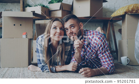 Happy couple is lying on floor in new house talking and smiling. Housing and relationship concept. 95201781