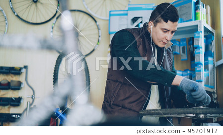Concentrated repairman in earphones is disassembling mechanism to repair it. People, maintenance and vehicle concept. Concentrated repairman in earphones is disassembling mechanism to repair it. People, maintenance and vehicle concept. 95201912