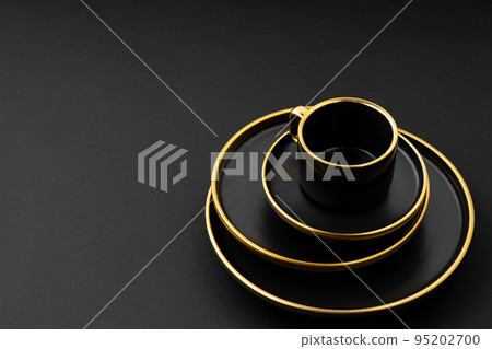 A set of black and golden ceramic plates and cup on a black background A set of black and golden ceramic plates and cup on a black background 95202700