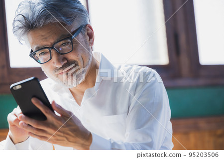 Gray-haired man using a smartphone 95203506