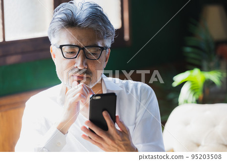 Gray-haired man using a smartphone Gray-haired man using a smartphone 95203508