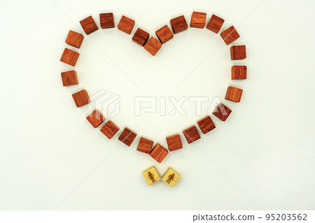Heart shaped wooden frame with red wood cubes above the couple Heart shaped wooden frame with red wood cubes above the couple 95203562