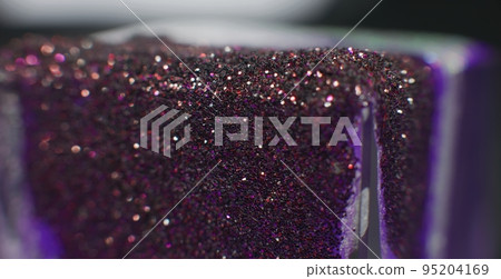 Glitter drip background. Bokeh light. Sequin texture. Defocused purple pink color sparkling particles on ice cube on dark black abstract banner. Glitter drip background. Bokeh light. Sequin texture. Defocused purple pink color sparkling particles on ice cube on dark black abstract banner. 95204169
