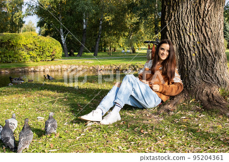 A girl sits on the shore of a pond A girl sits on the shore of a pond 95204361