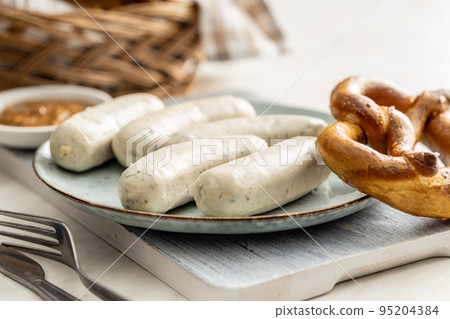 Traditional Bavarian white sausages on plate and pretzes. 95204384