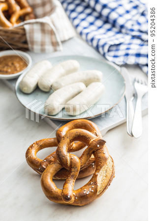 Traditional Bavarian white sausages on plate and pretzes. Traditional Bavarian white sausages on plate and pretzes. 95204386