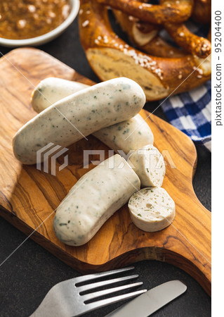Traditional Bavarian white sausages on cutting board and pretzels. Traditional Bavarian white sausages on cutting board and pretzels. 95204400