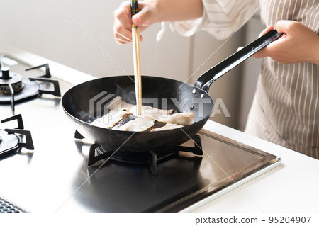 一個人在鑄鐵平底鍋裡煮培根 95204907