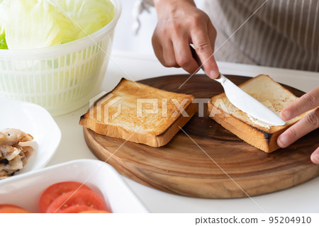 為三明治塗上新鮮出爐的麵包的人 95204910