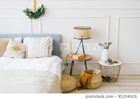 Cozy bedroom with a bed and a Christmas wreath, bedside table 95204929